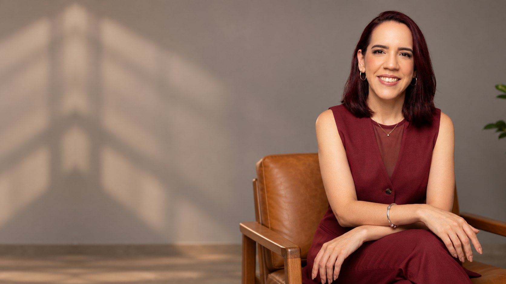 Alessandra Macedo, nutricionista, sorrindo, sentada em uma poltrona de couro no consultório